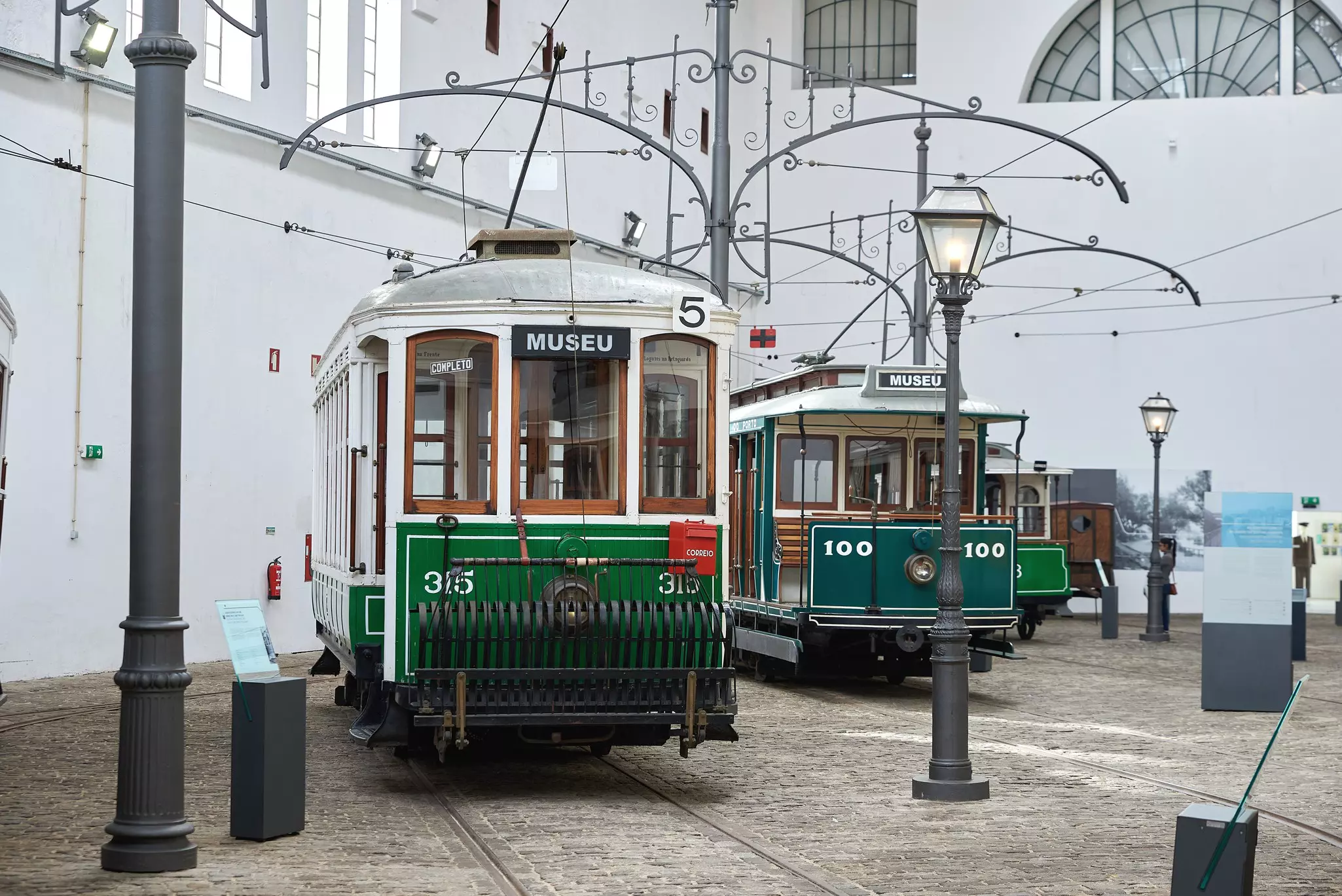 Vintage green and white trams on tracks in an indoor exhibit