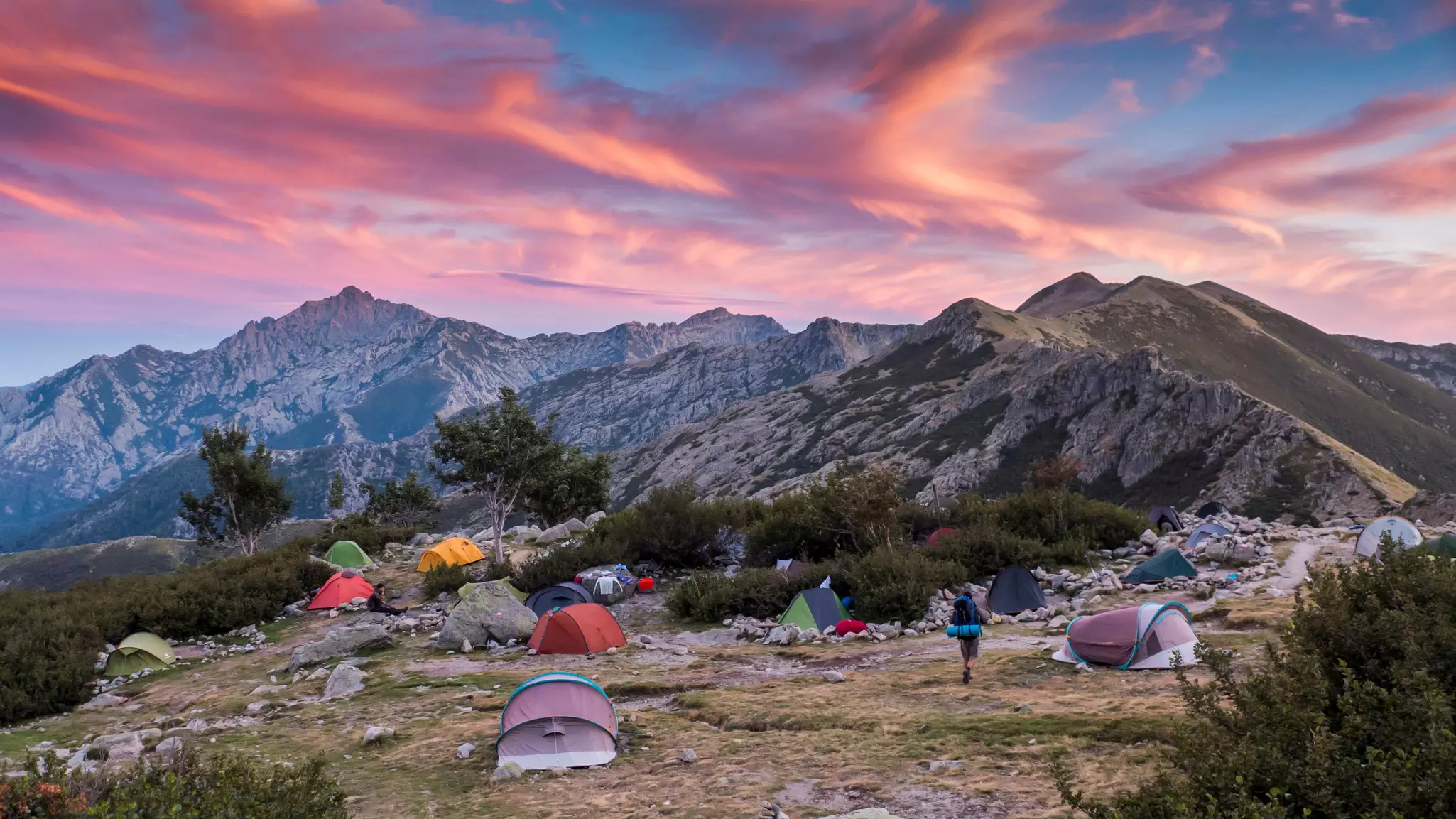 Several two-person tents set up at a campsite in a mountainous region.