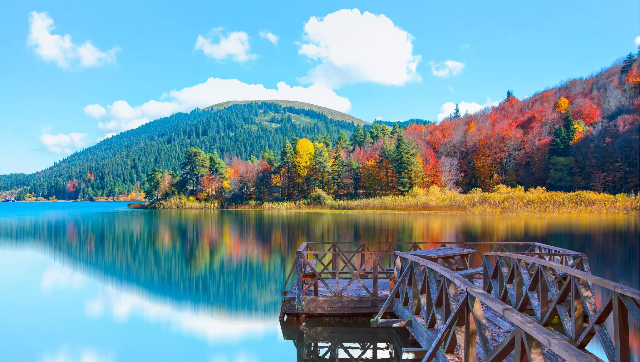 A scenic lake surrounded by trees in fall colors of red, gold, green and yellow.