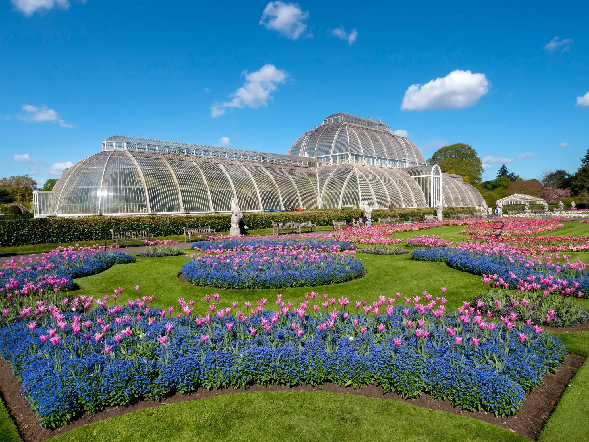 Flower beds form patterns in front of Kew Gardens Palm House in London, UK