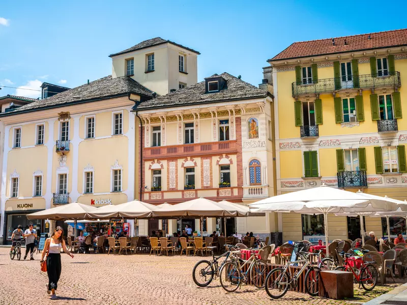Pedestrian square with colorful houses and people at cafe outdoor terrace on Piazza Collegiate in old Bellinzona Ticino Switzerland 