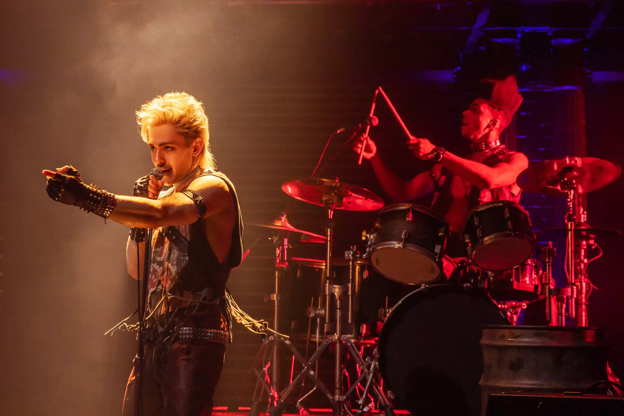 A singer and a drummer performing on stage.