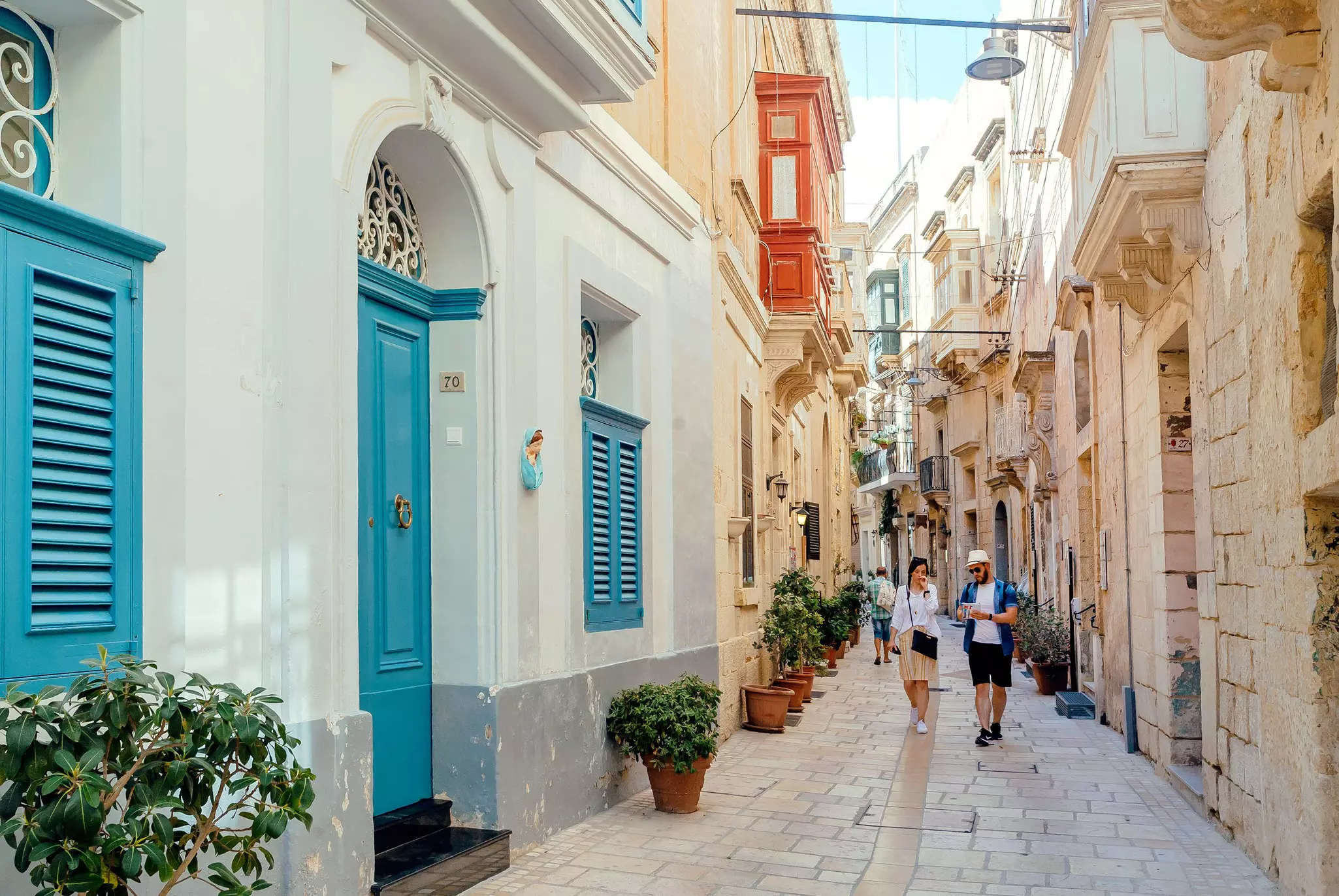 Tourists walking down narrow streets with wooden doors and historical houses in Vittoriosa.