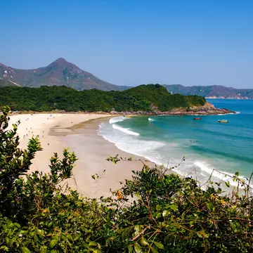 A wide sandy beach surrounded by mountain peaks.