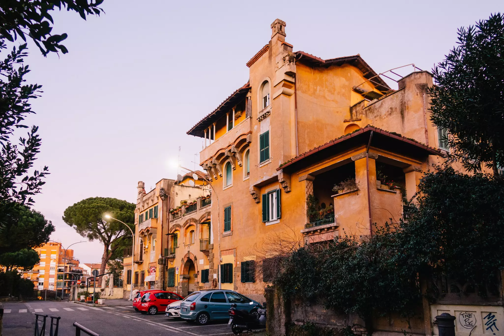 A building with orange facade facing a tree and cars parked outside