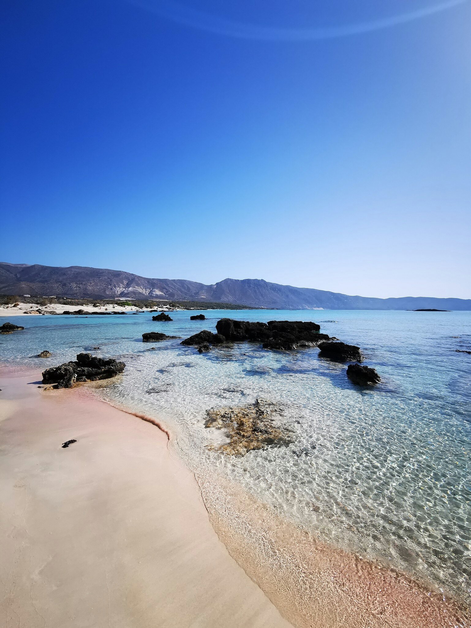 Elafonisi Beach in Crete, with pink sand and rocks protruding from the crystal clear water during the summer months.
