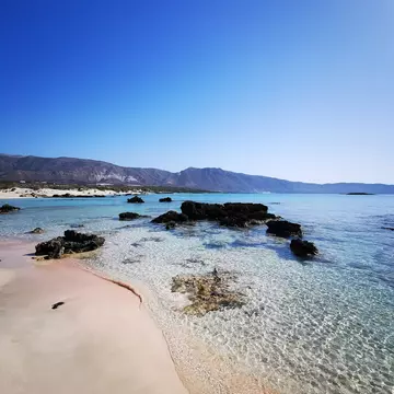 Elafonisi Beach in Crete, with pink sand and rocks protruding from the crystal clear water during the summer months.