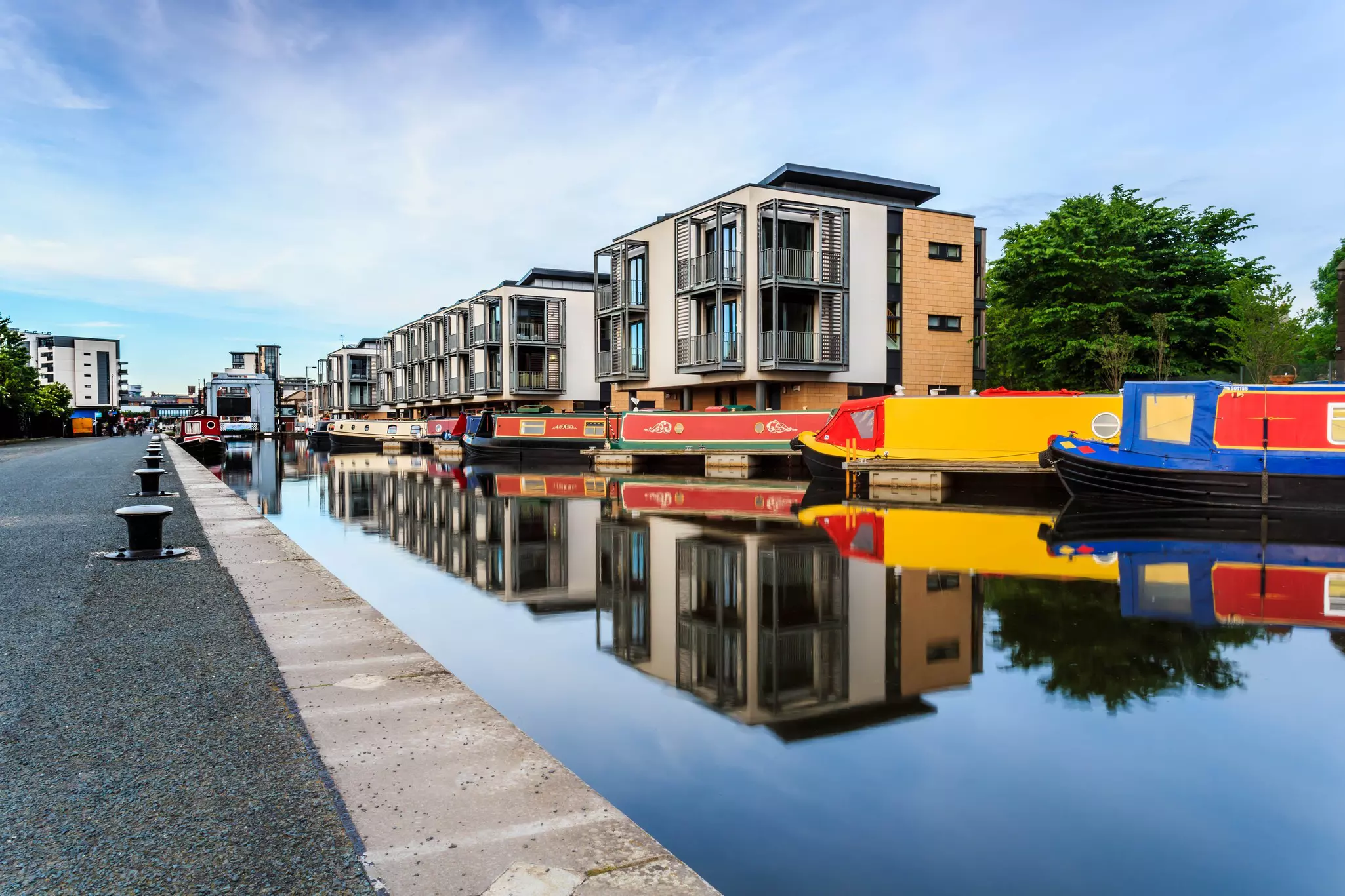 Colorful boats on the Union Canal in Edinburgh, with modern buildings on the banks.