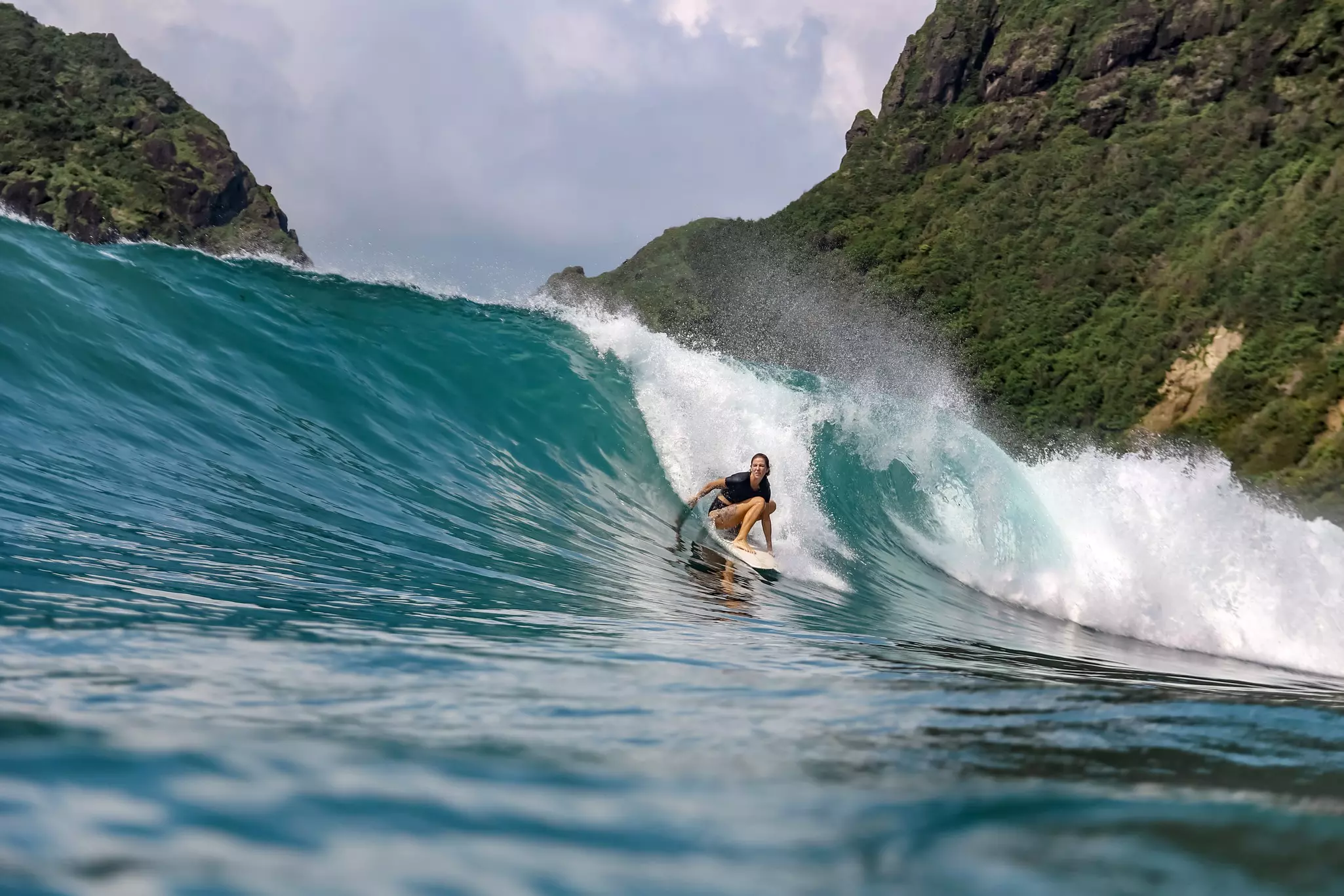 A woman surfing off the coast of Bali, Indonesia.