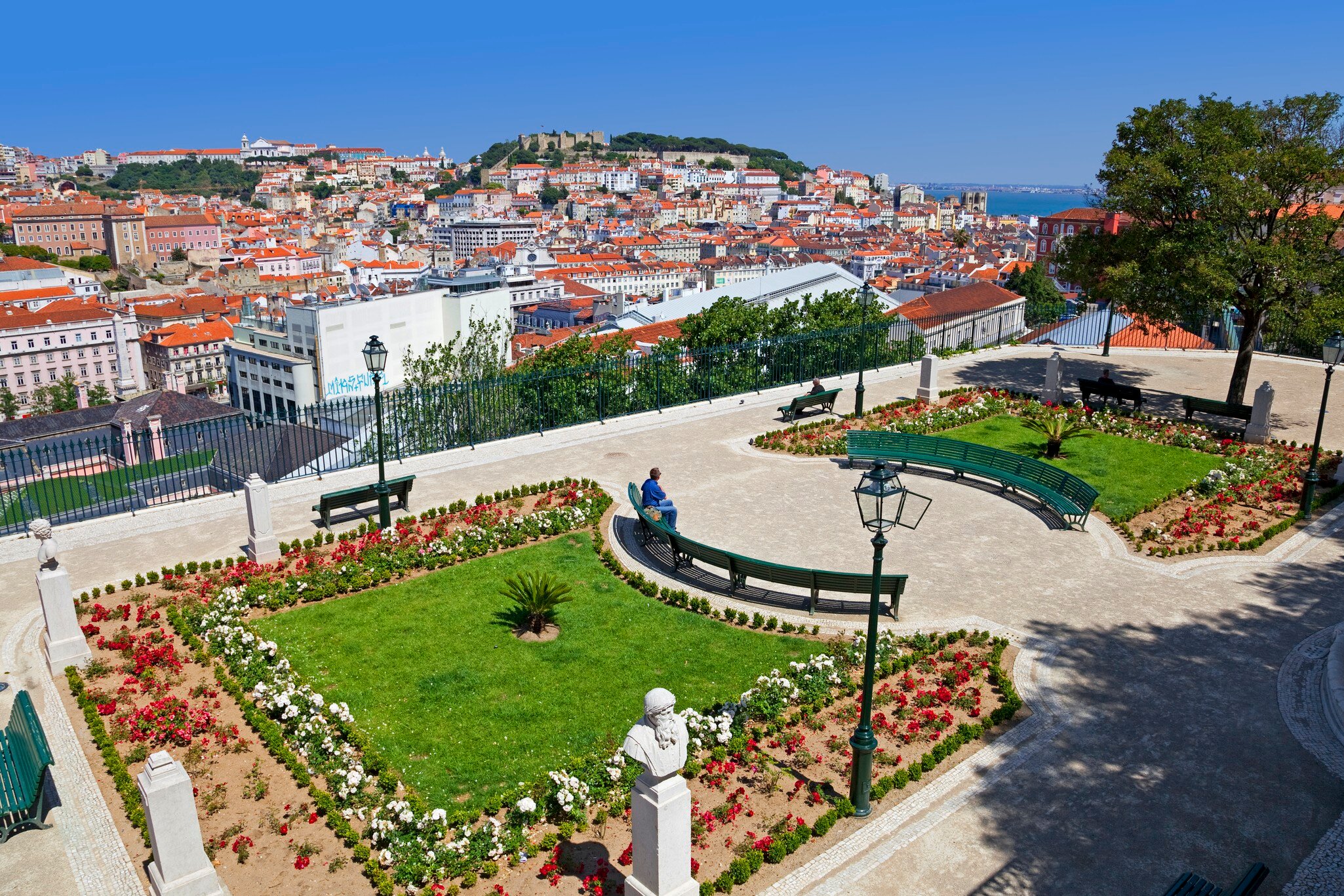 Lisbon, Portugal - May 26, 2013: Miradouro de Sao Pedro de Alcantara viewpoint or Belvedere in Bairro Alto District. View of the Baixa and Alfama District and Castelo Sao Jorge aka Saint George Castle