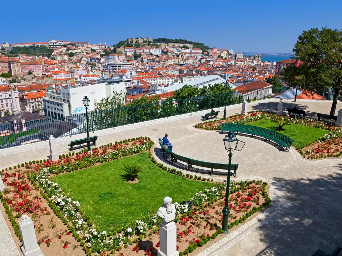 Lisbon, Portugal - May 26, 2013: Miradouro de Sao Pedro de Alcantara viewpoint or Belvedere in Bairro Alto District. View of the Baixa and Alfama District and Castelo Sao Jorge aka Saint George Castle