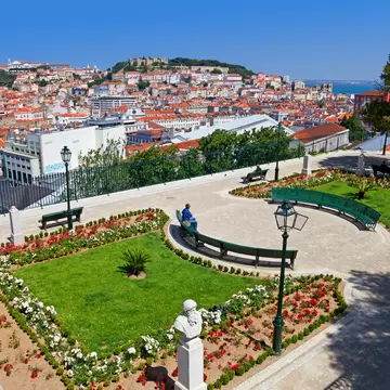 Lisbon, Portugal - May 26, 2013: Miradouro de Sao Pedro de Alcantara viewpoint or Belvedere in Bairro Alto District. View of the Baixa and Alfama District and Castelo Sao Jorge aka Saint George Castle