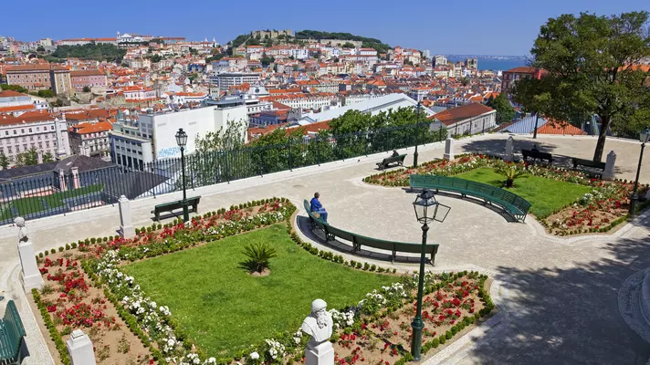 A viewpoint over buildings towards a river, with lawns and flowerbeds