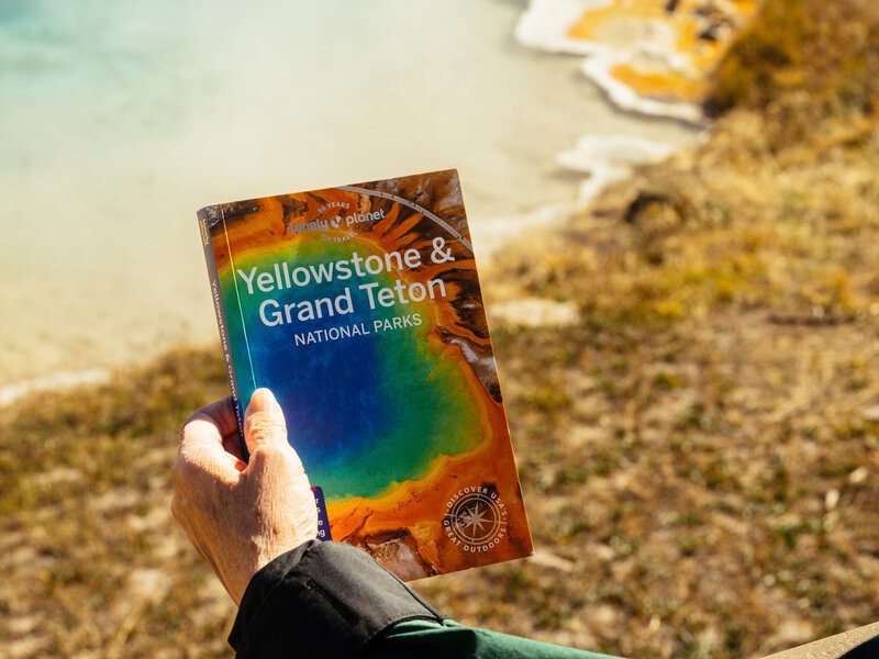 Lonely Planet Yellowstone Book in front of Silex Spring, a hot spring in the Lower Geyser Basin. September 2025.