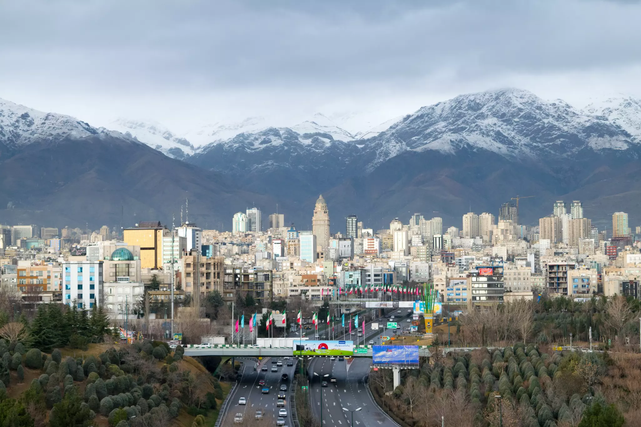 A city skyline at the foot of a snow-capped mountain range.