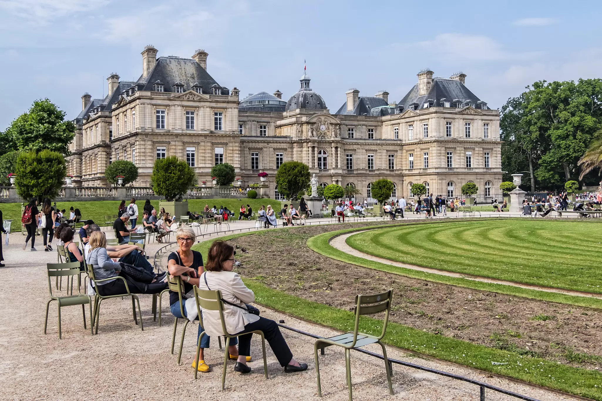 People relaxing in the famous green chairs in Luxembourg Garden.