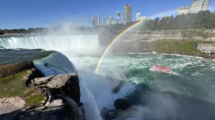 The falls creating a heavy mist with green blue water below. 
