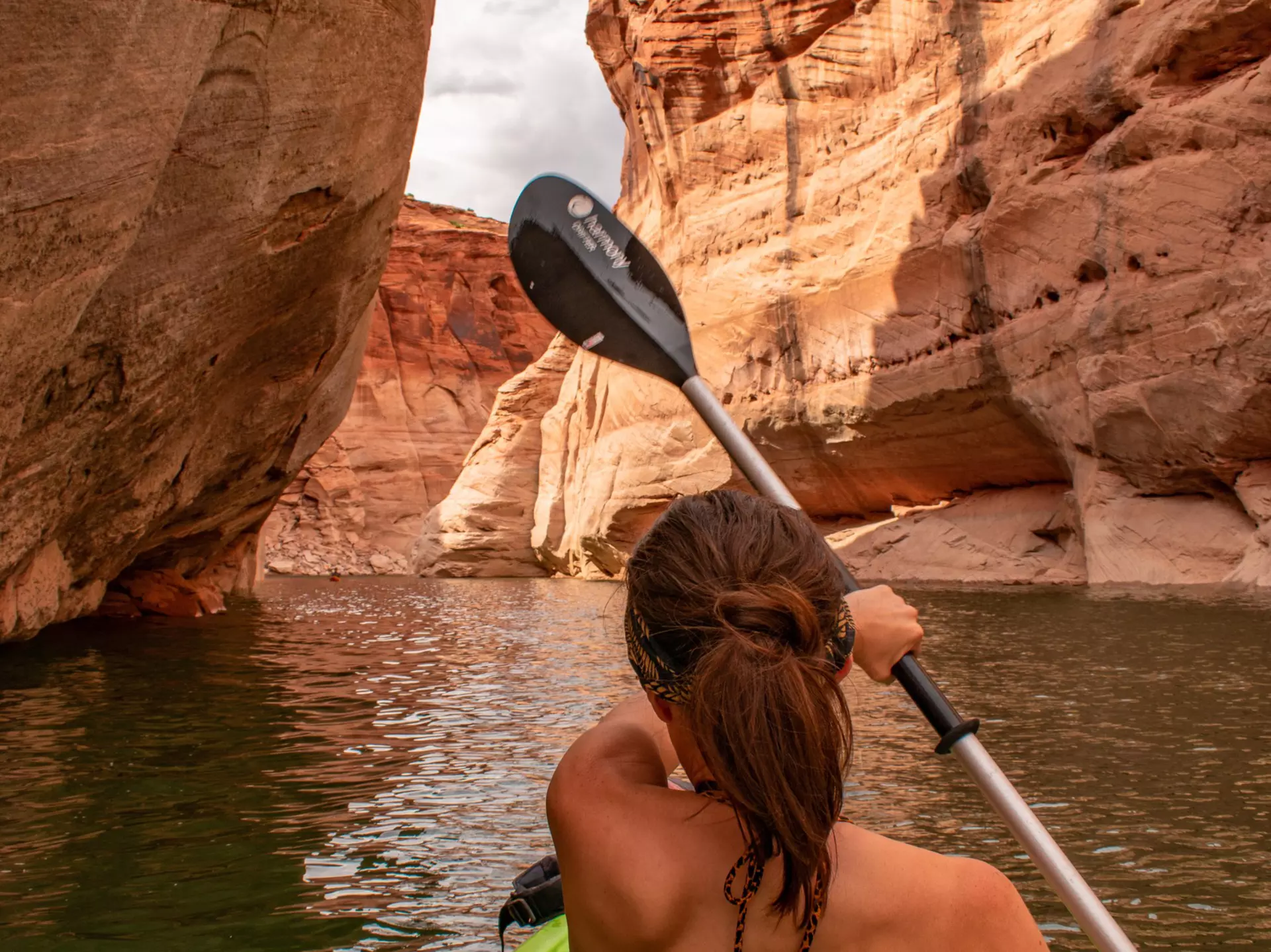 A person kayaks through a canyon of reddish rock.