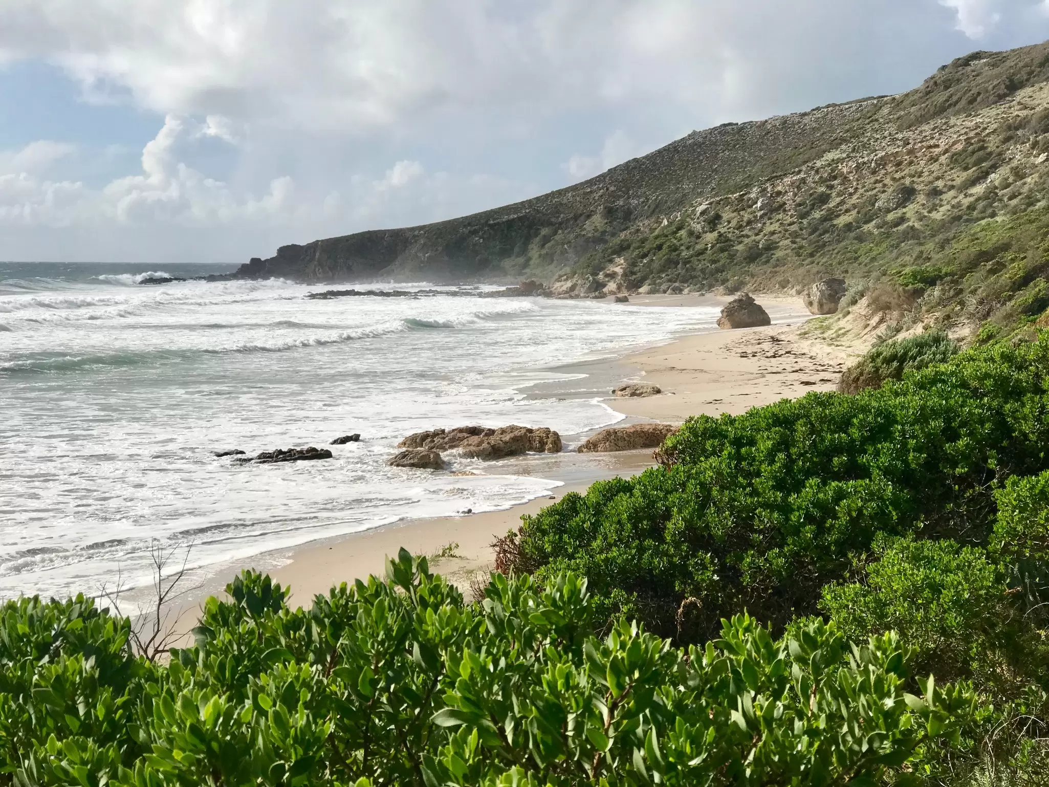 Side shot of Stokes Bay beach on Kangaroo Island with ocean surf and cloudy sky above