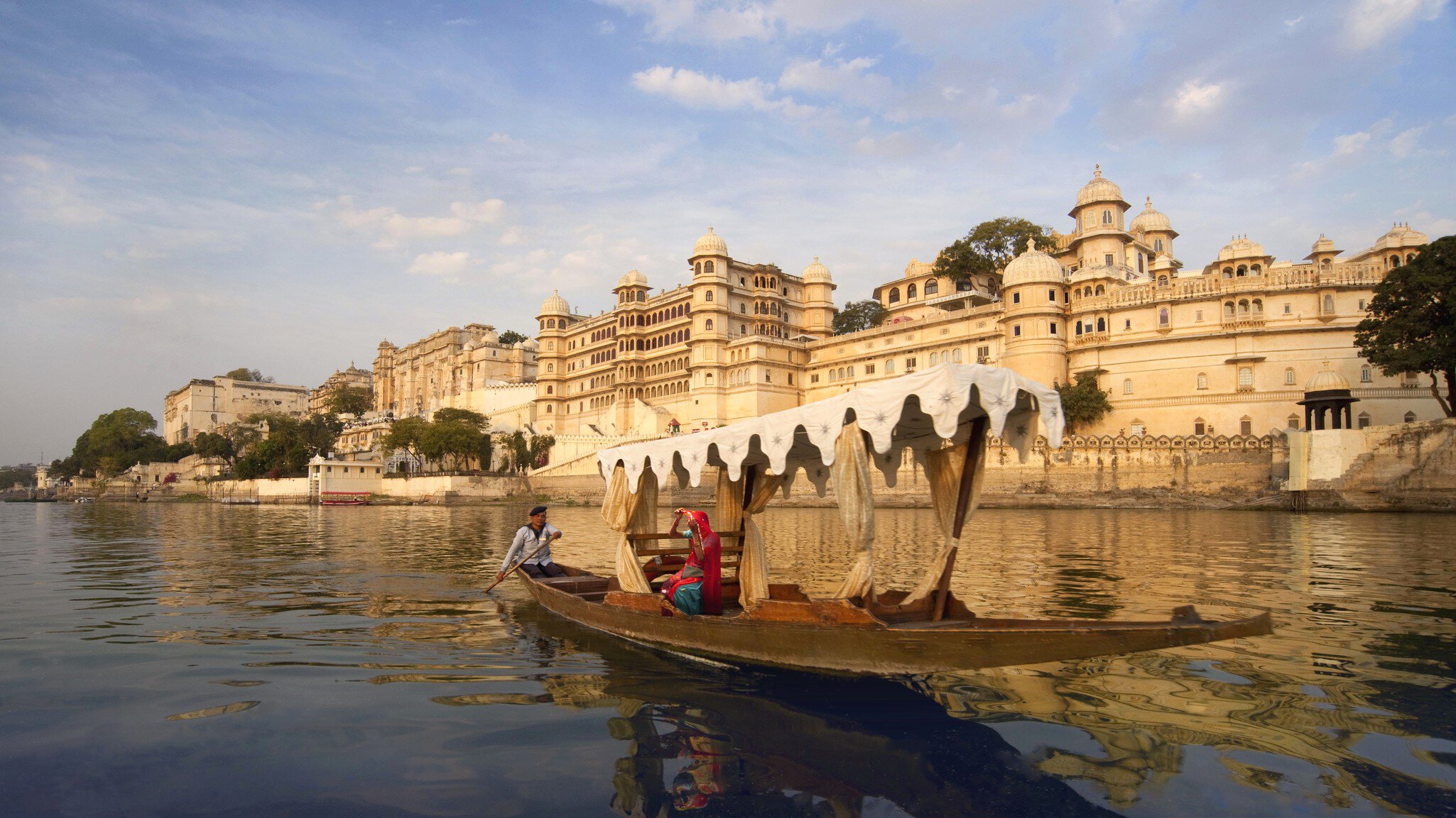 Woman on a boat on Lake Pichola beside the City Palace, Udaipur, Rajasthan, India.