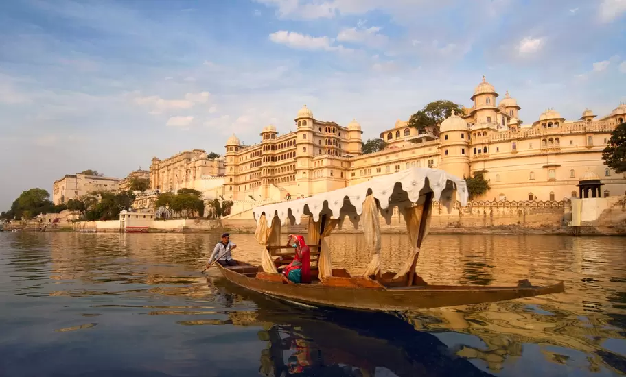 A woman on a boat on Lake Pichola beside the City Palace in Udaipur, Rajasthan, India.
