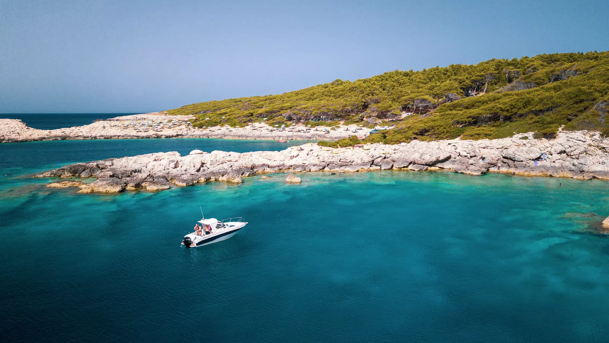 Boat moored offshore by a rocky cove in the Tremiti archipelago, Puglia. 