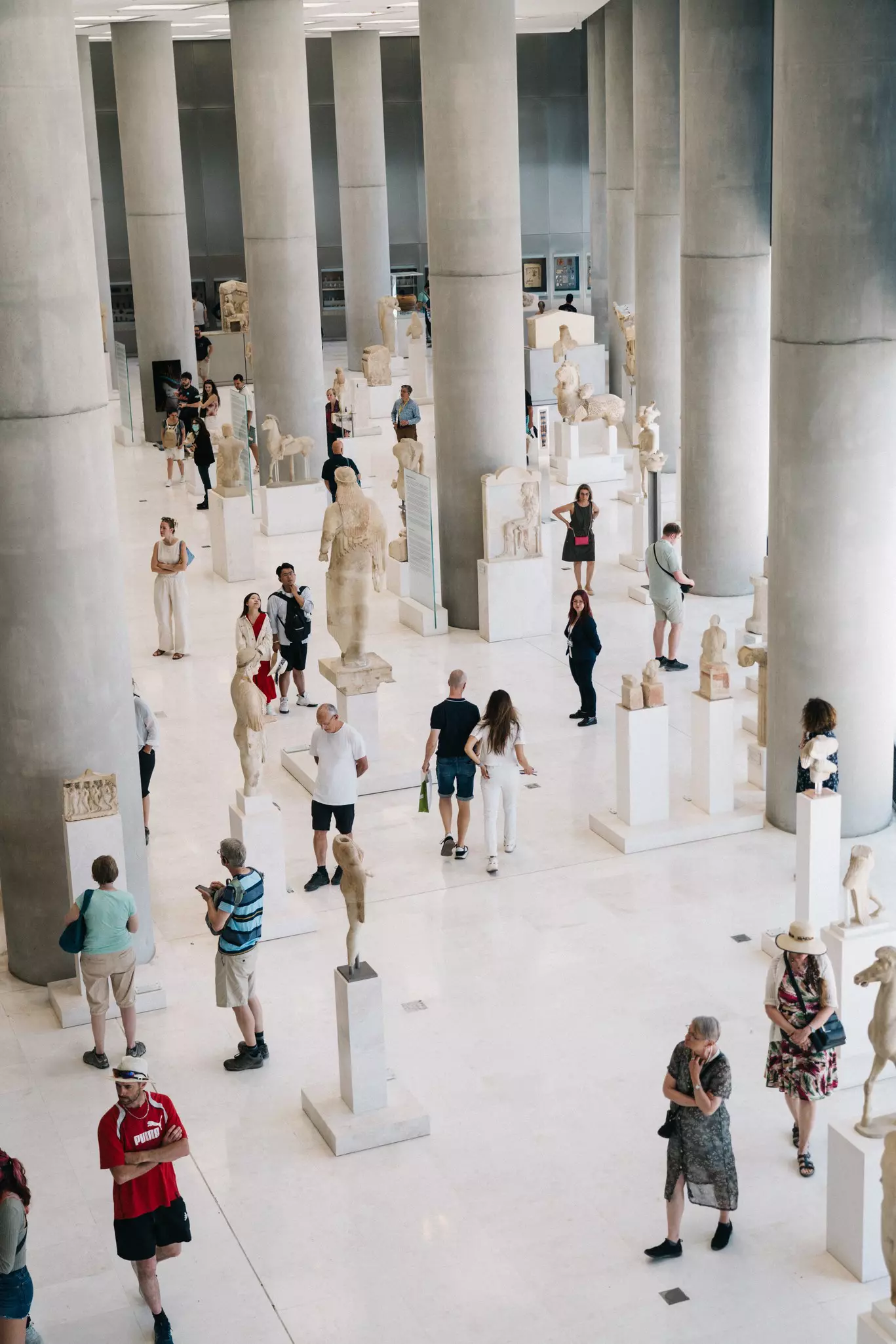 Visitors to a museum showing ancient Greek artworks and sculptures.