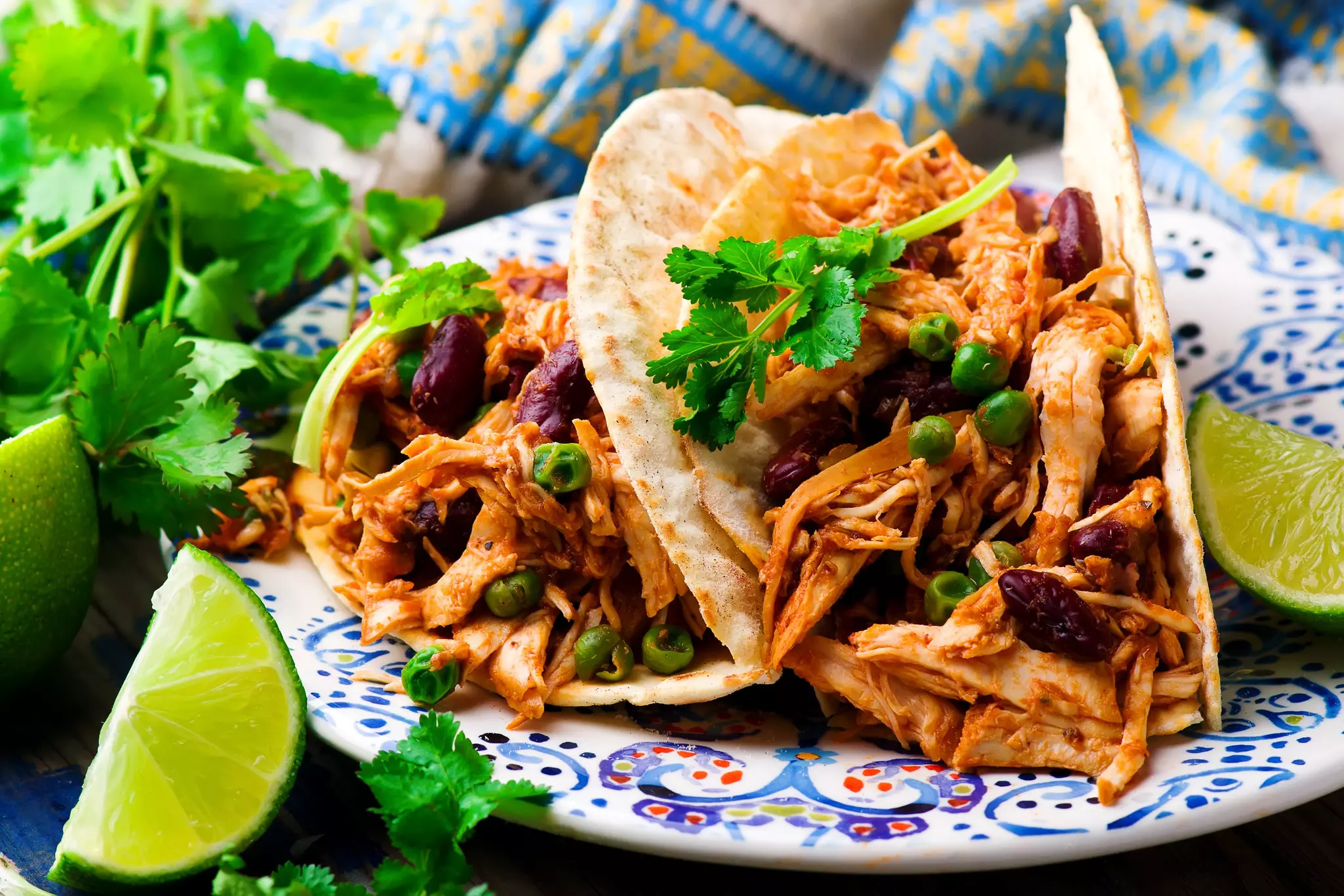 A plate with two shredded chicken tacos and two slices of lime.