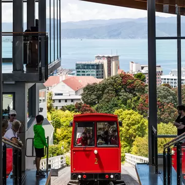People wait to get on the red Wellington Cable Car as it climbs above the suburb of Lambton Quay.