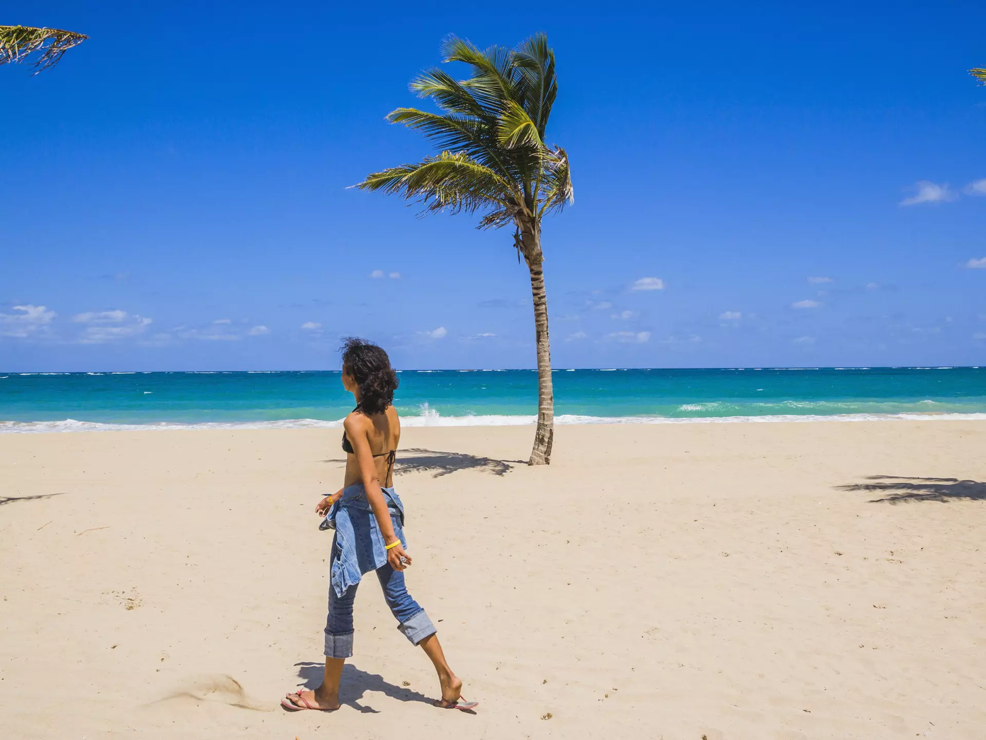 A woman walks on a beach in San Juan, Puerto Rico on a bright sunny day.
546160219