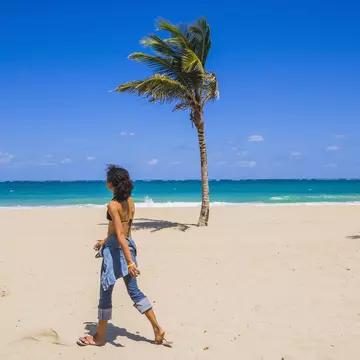 A woman walks on a beach in San Juan, Puerto Rico on a bright sunny day.
546160219