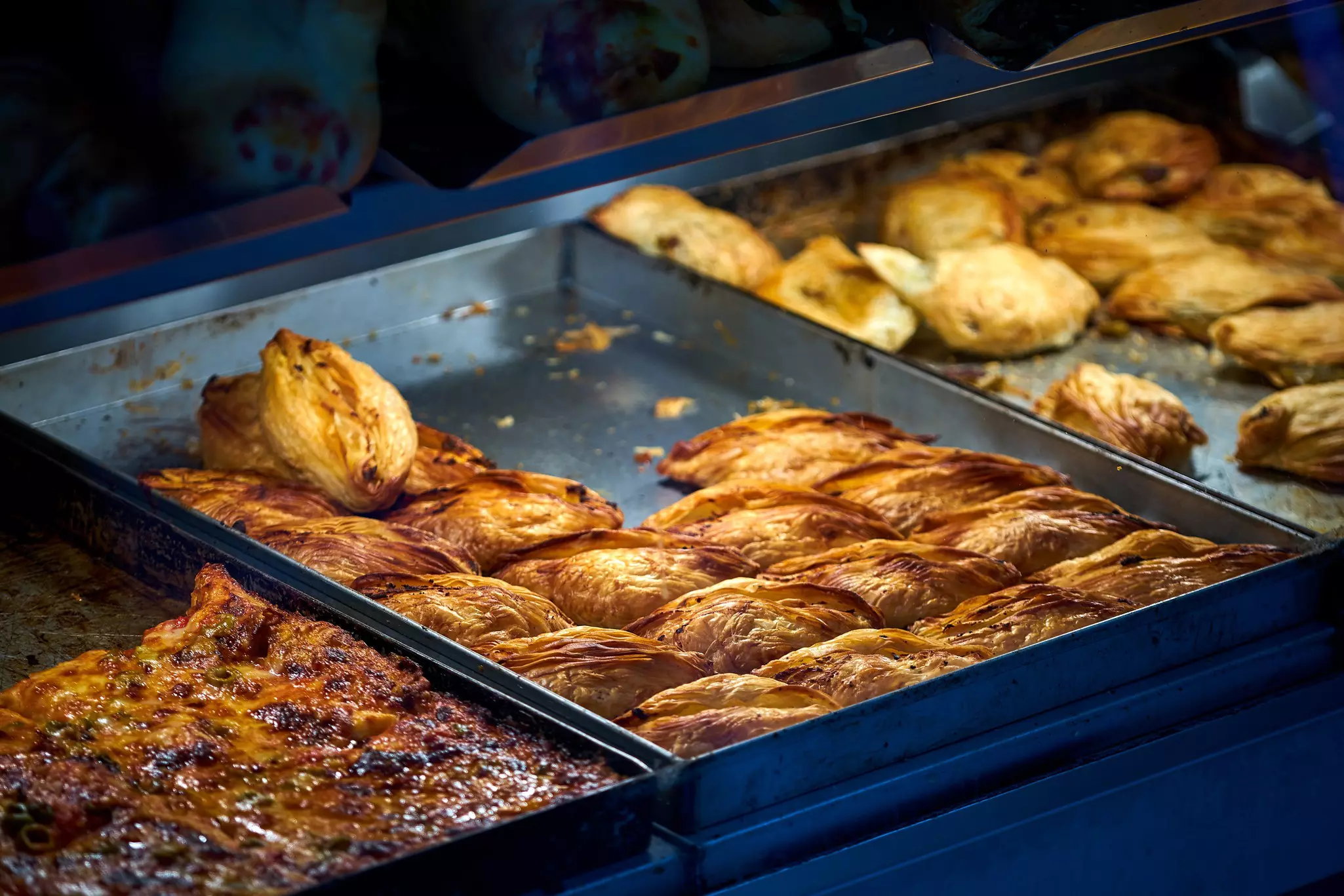 Three trays filled with different pastries in a shop.