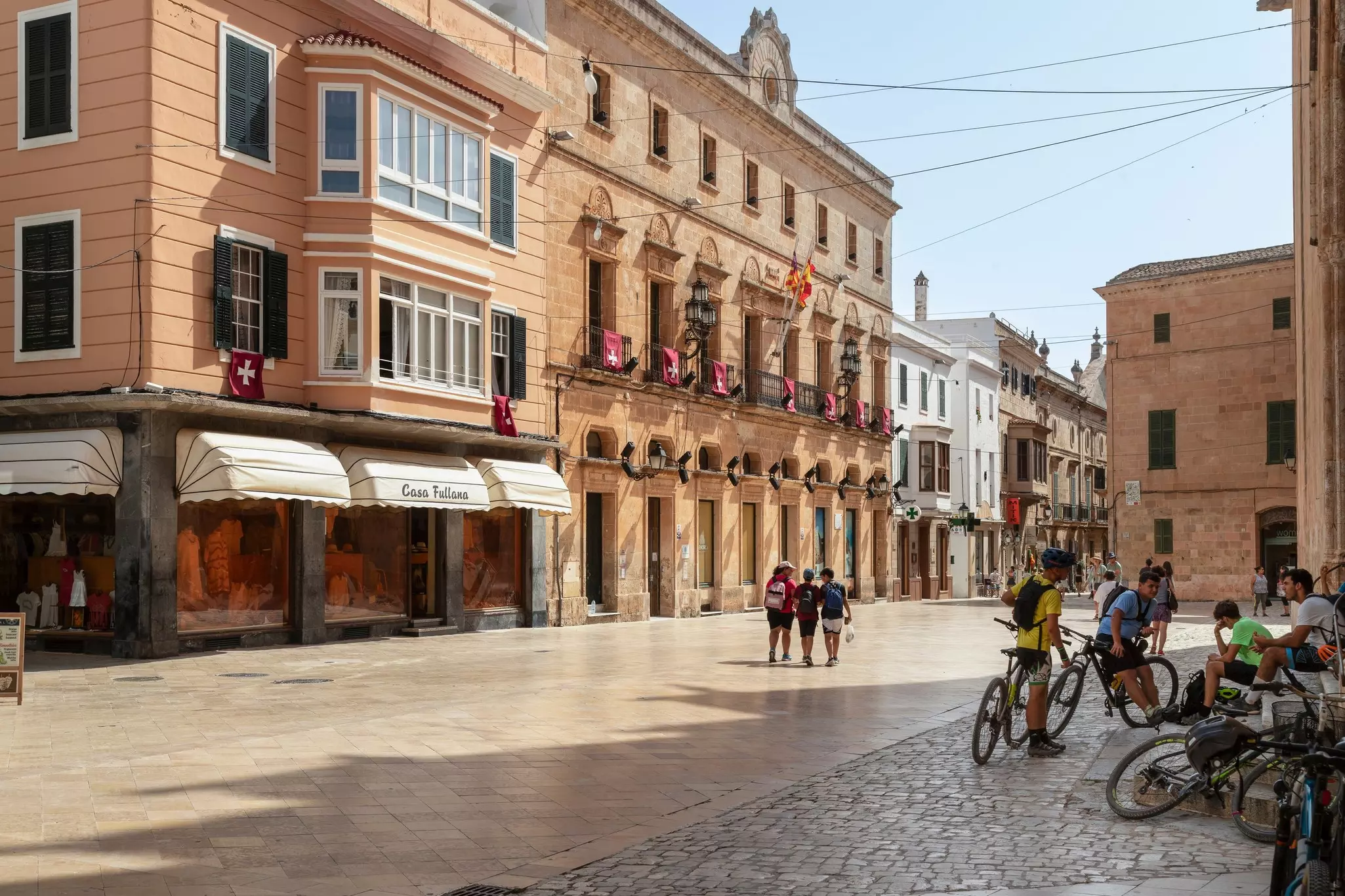 School boys with bicycles in the Plaça de la Catedral in the city of Ciutadella with the Consell Insular de Menorca in the background.