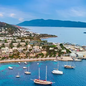 A coastal settlement with several boats moored near the sandy beach; Bodrum, Turkey
