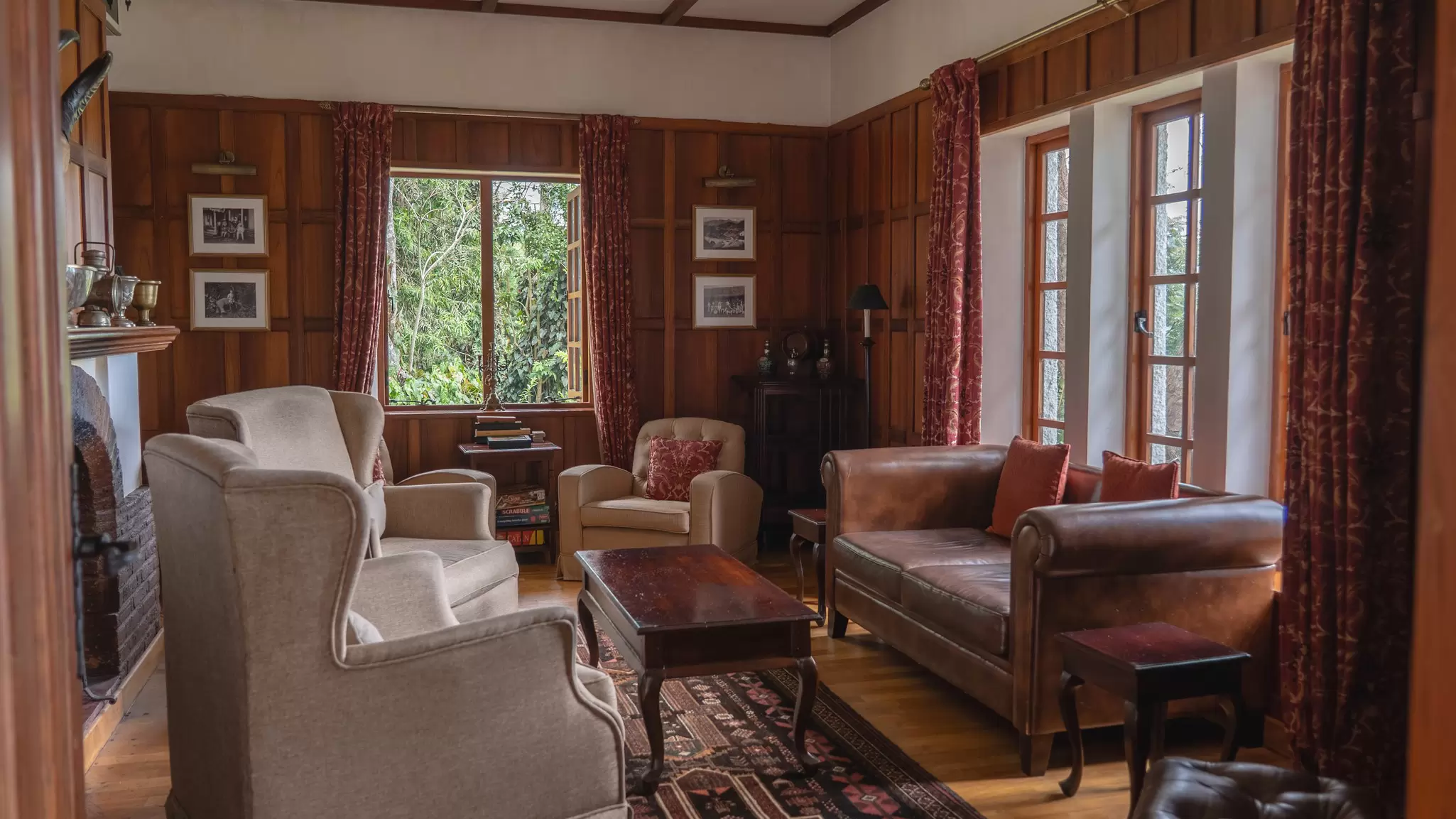 A wood-paneled sitting room with upholstered seating and period furnishings in Thotalagala hotel in Haputale, Sri Lanka