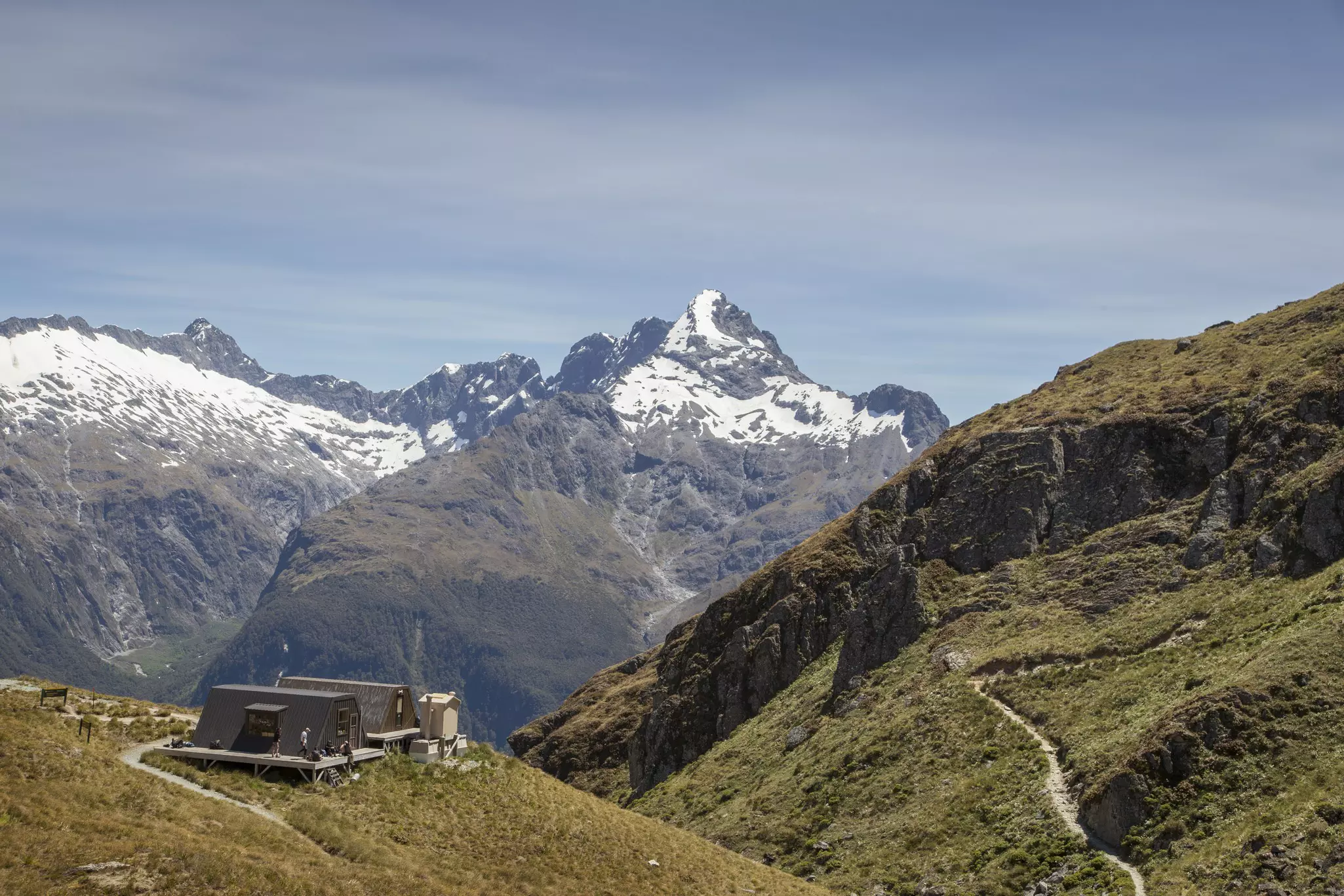 Two buildings with surrounding decks at the edge of a remote mountain path.