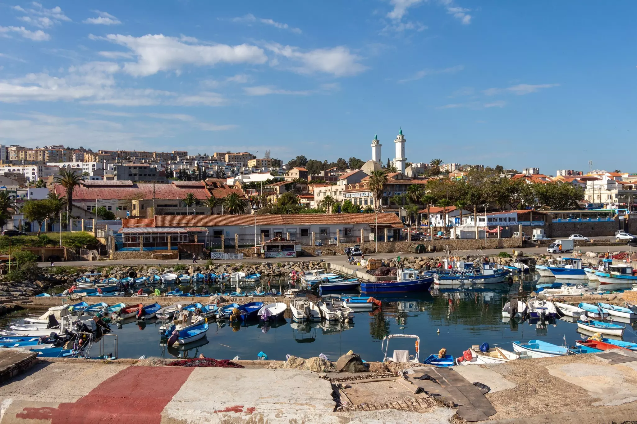 Beautiful panoramic view of the old port in Tipaza, Algeria, with fishing boats, and the city in the background, with the white mosque.