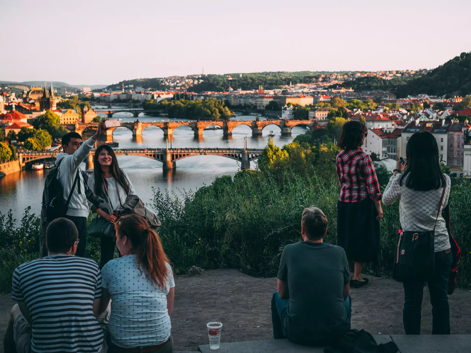 People enjoying the sunset over a city with a river running through the center of it