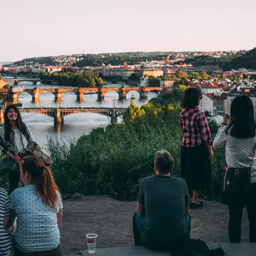 People enjoying the sunset over a city with a river running through the center of it