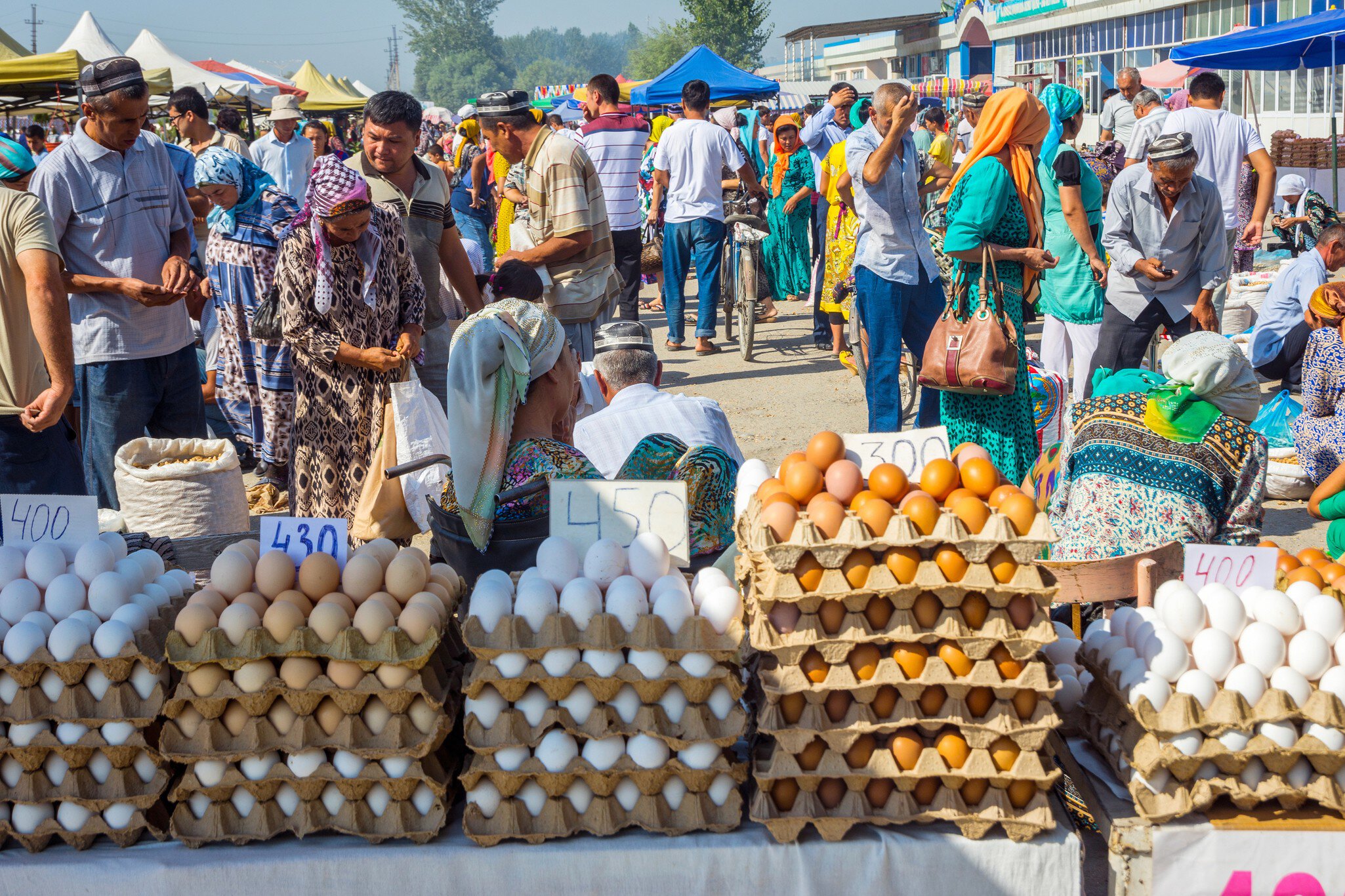 MARGILAN, UZBEKISTAN - AUGUST 21: Eggs for sale and a crowd of people visiting Kumtepa bazaar. Market is one of the biggest in the area running once a week. August 2016; Shutterstock ID 623624792;