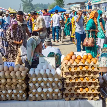 MARGILAN, UZBEKISTAN - AUGUST 21: Eggs for sale and a crowd of people visiting Kumtepa bazaar. Market is one of the biggest in the area running once a week. August 2016; Shutterstock ID 623624792;