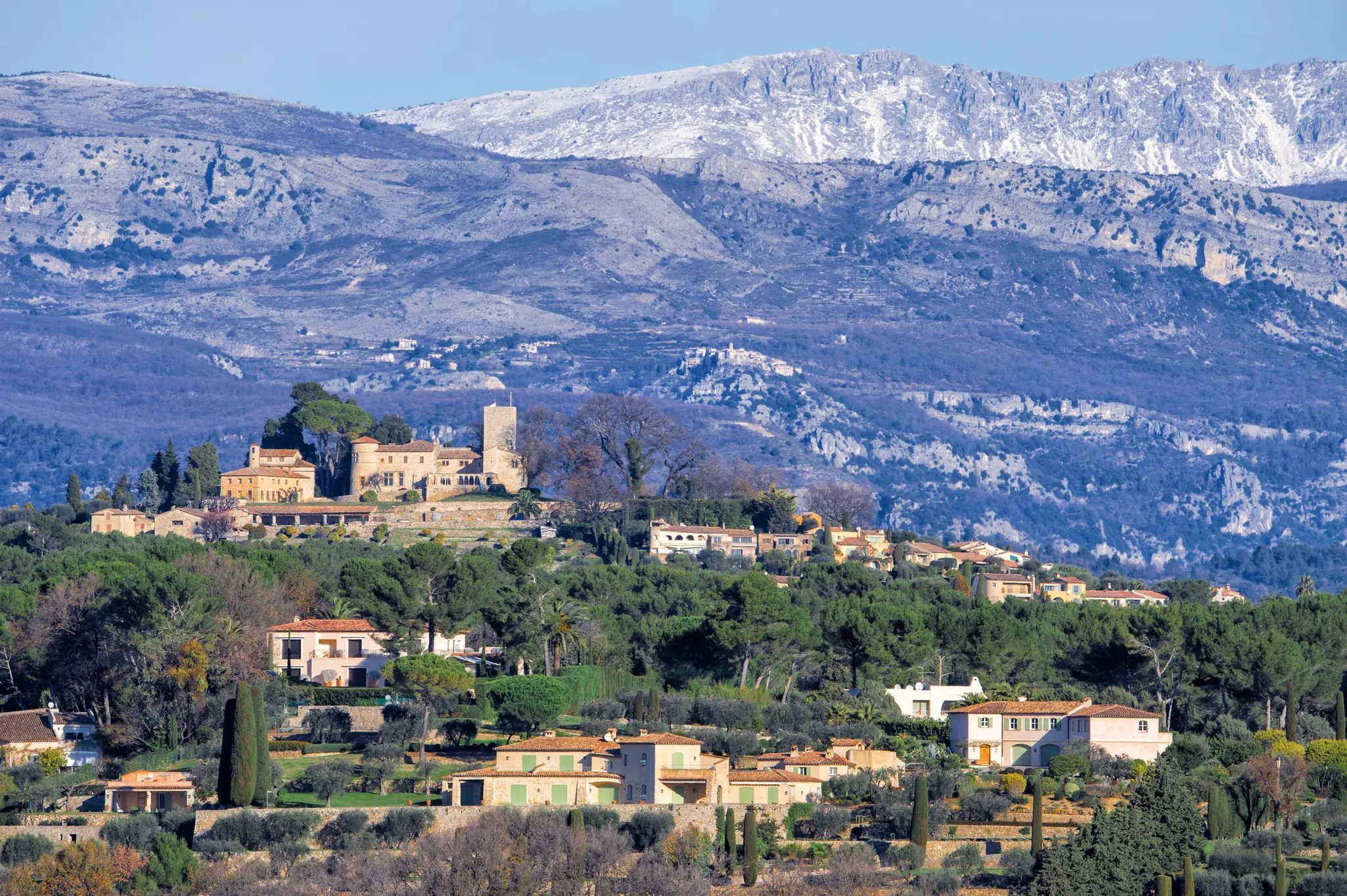 A hilltop town with fortifications backed by a snow-dusted mountain range