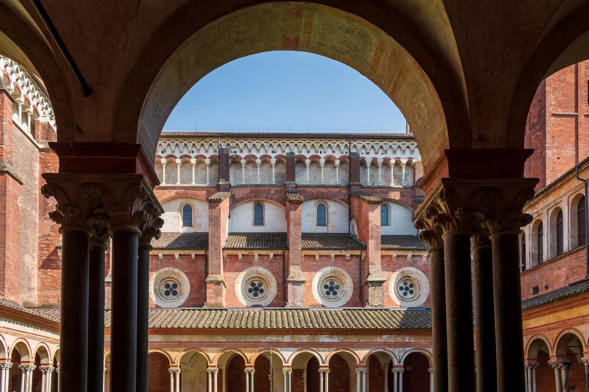 A view from a covered passageway of the side of a Gothic church.