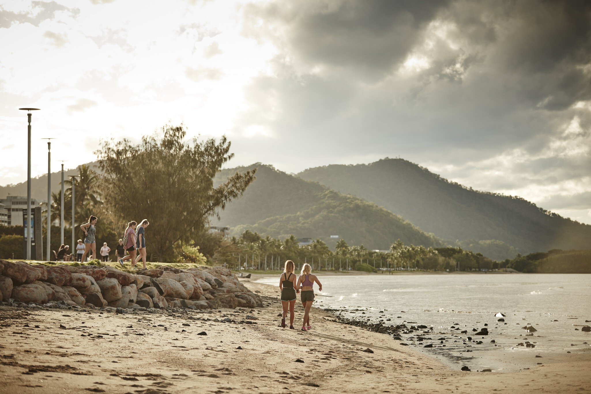 People walking across the beach during sunset in Cairns, Queensland, Australia.