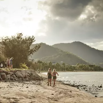 People walking across the beach during sunset in Cairns, Queensland, Australia.