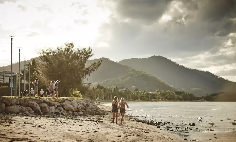People walking across the beach during sunset in Cairns, Queensland, Australia.