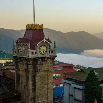 Darjeeling clock tower in front of a sweeping view of the mountains. Darjeeling, West Bengal, India.