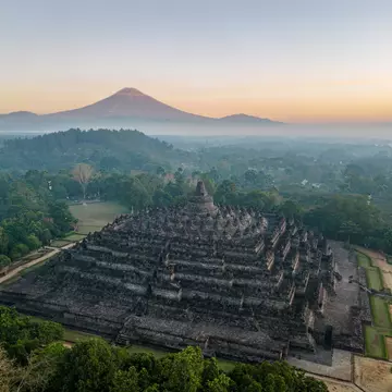 A view of Borobudur Temple in Java, Indonesia with the Merapi volcano in the background.