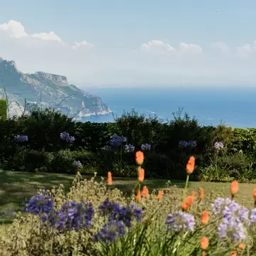 Panoramic view of the Villa Rufolo in Ravello, Italy, with flowers in the foreground.