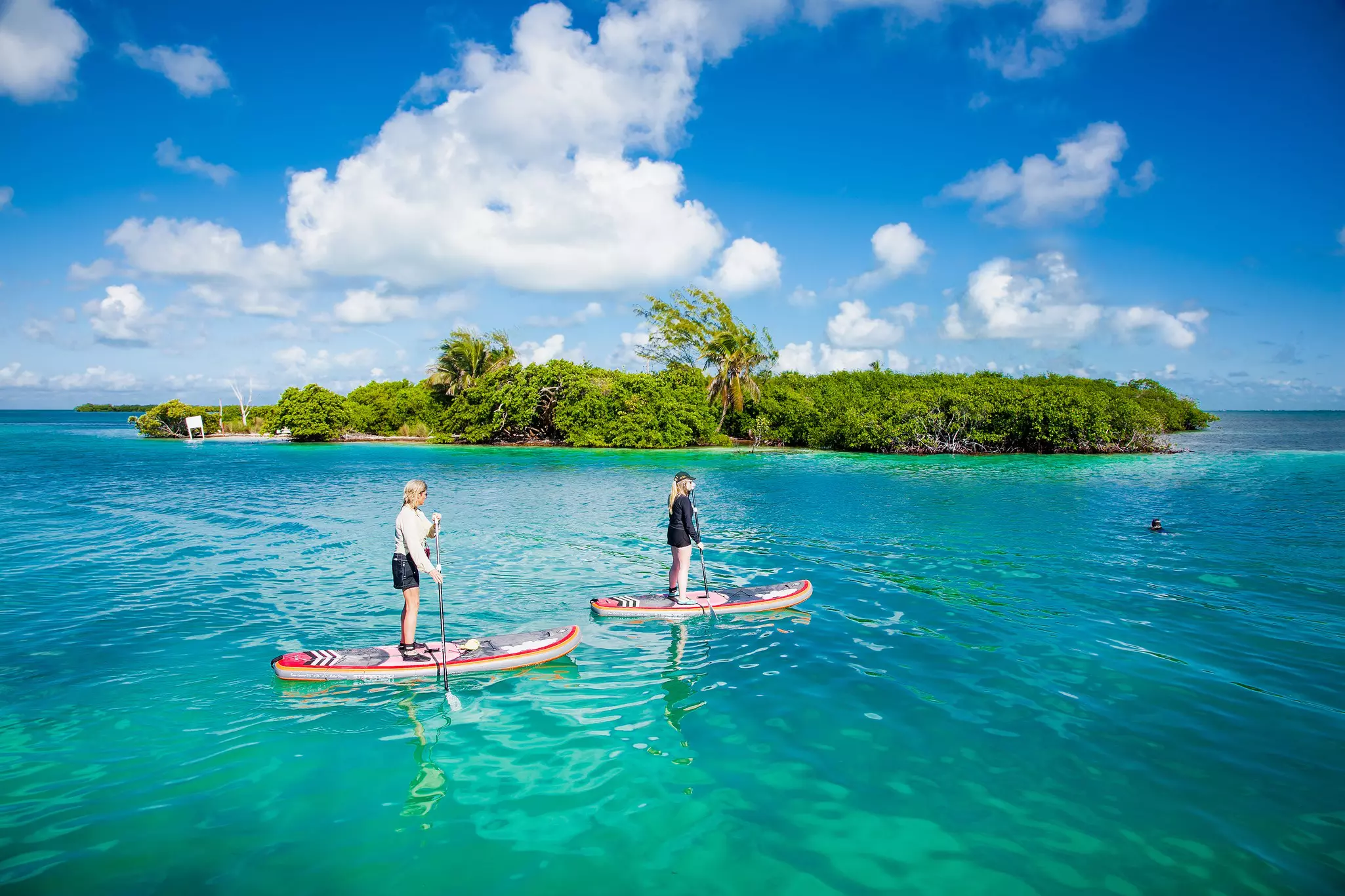 People paddleboard in the waters by Caye Caulker island.